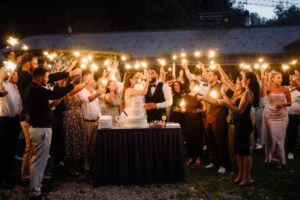 Guests with sparklers gathered around the wedding cake at night
