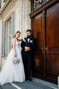 Bride and groom in front of the tall wooden door of an old building