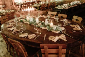 Round table laid for the wedding dinner with candles and greenery
