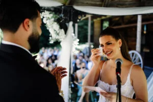 Bride laughing as she speaks into a microphone during the ceremony
