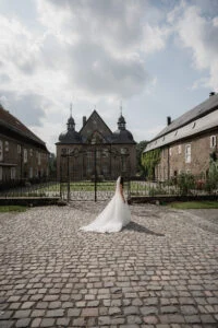 Bride walking across the cobbled courtyard of a manor house in Germany