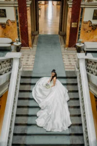 Bride walking up a marble staircase with her long train behind her