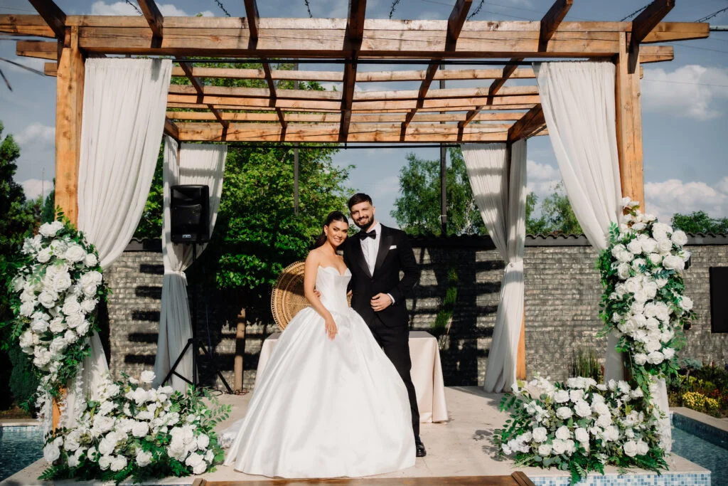 Bride and groom standing under a flower-covered pergola after the ceremony