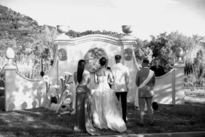 Black and white photograph of the ceremony in front of a stone gateway
