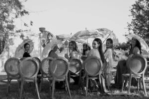 Black and white photograph of guests seated on cane chairs during the ceremony