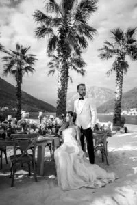 Black and white photograph of the bride and groom at the table under the palms
