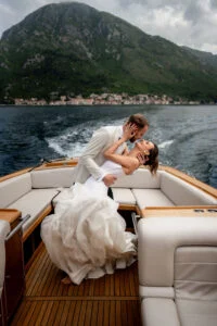 Bride and groom on the deck of the boat, the mountains of the bay behind