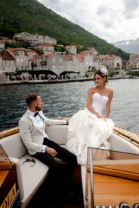 Bride and groom seated on the boat in front of Perast