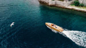 Aerial view of the wooden boat passing close to the rocky shore