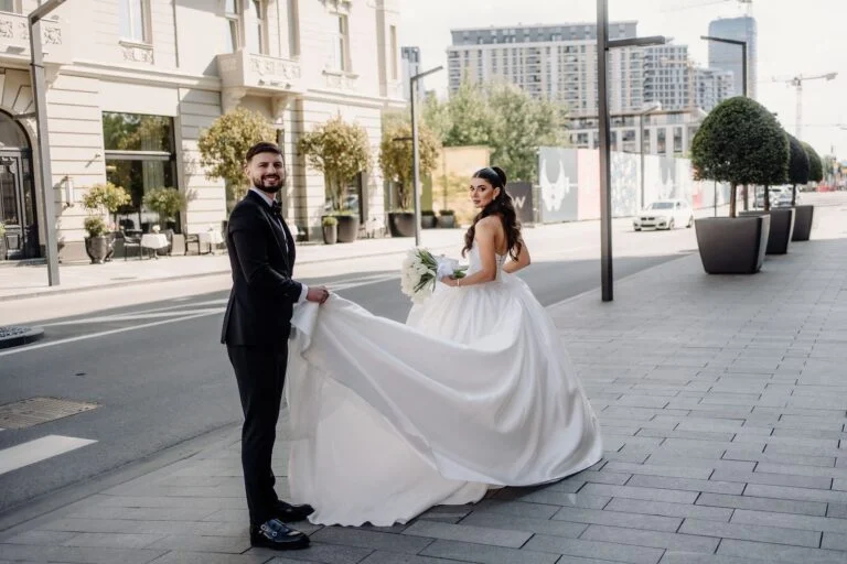 Groom holding the bride's train on a Belgrade street