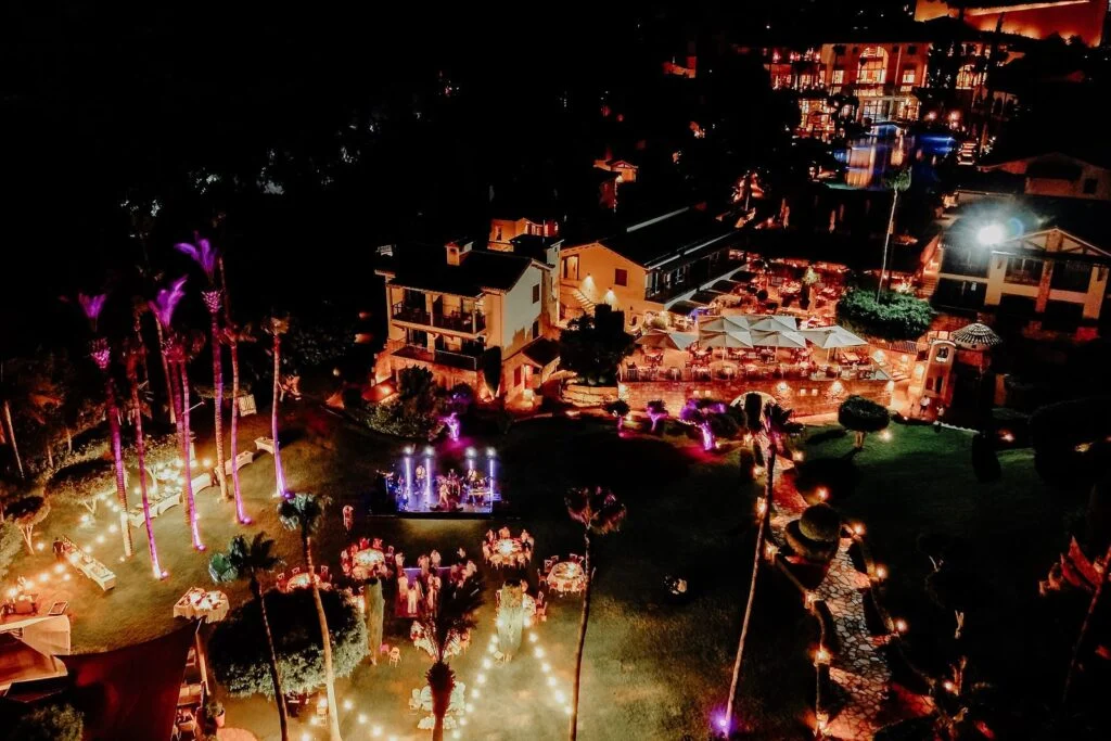 Aerial view at night of a lit garden party in Cyprus, the stage and dinner tables seen from above