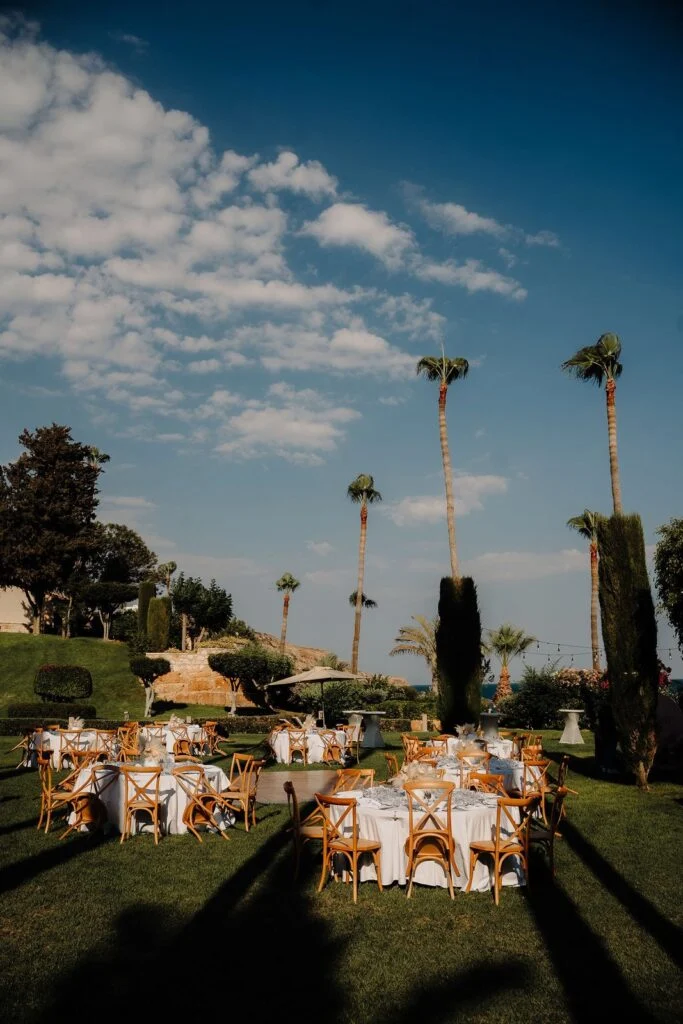 Dinner tables set under palm trees at dusk