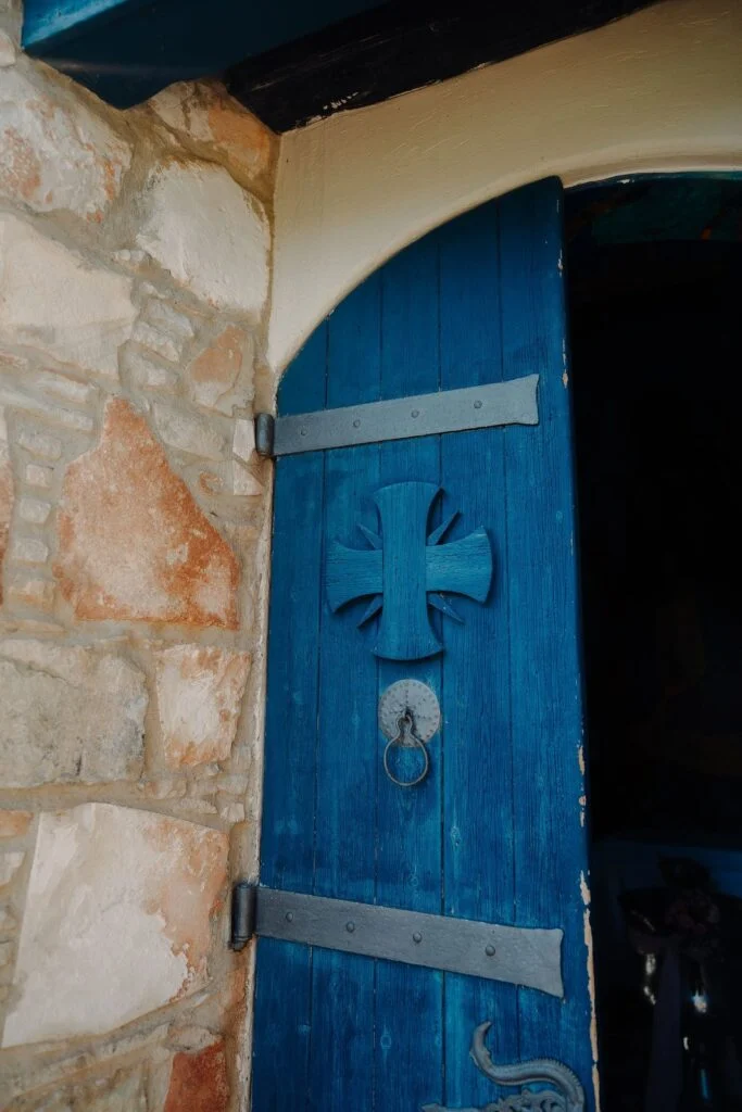 Blue wooden door with an iron cross in a stone wall