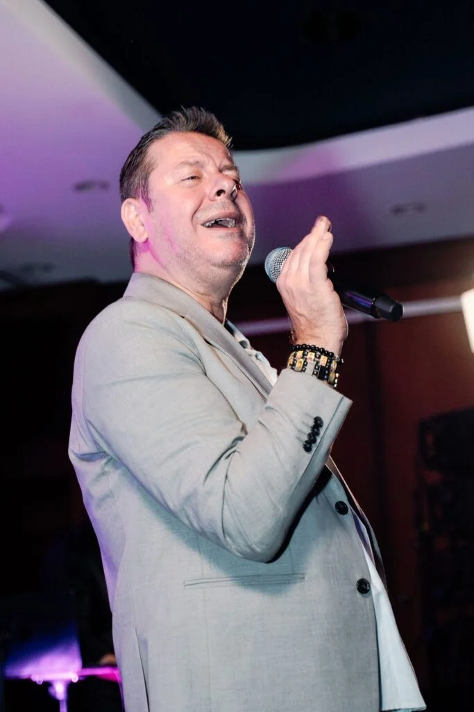 Singer Vlado Georgiev performing into a handheld microphone under the stage lights