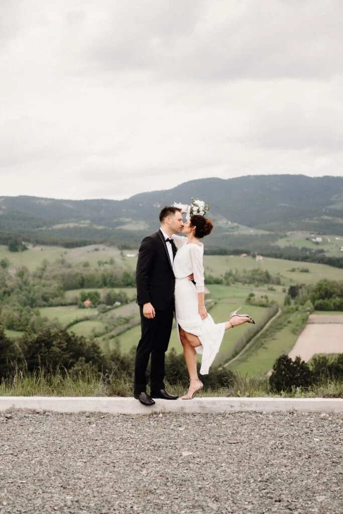 Bride and groom on a mountain road above green fields at Divčibare