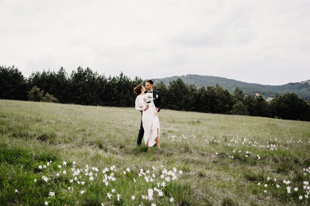 Bride and groom small in a wide mountain meadow