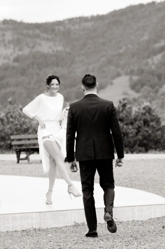 Black and white photograph of the bride and groom walking away across a terrace