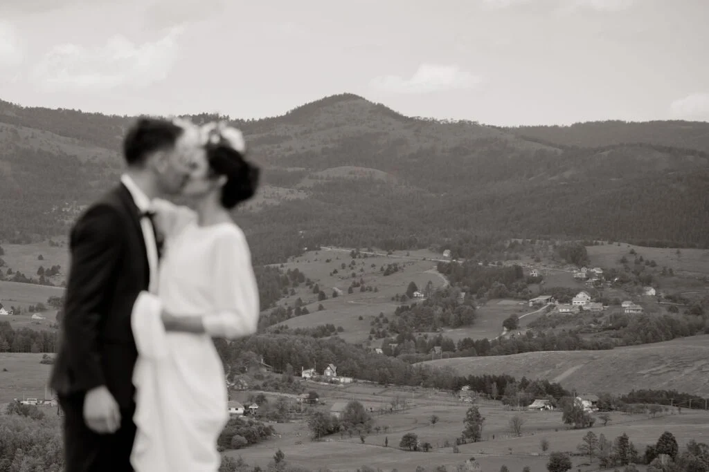 Black and white photograph of the couple kissing above the valley