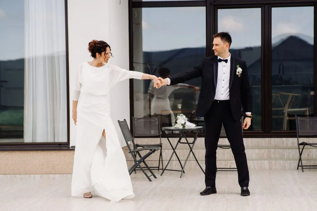 Bride and groom on the terrace of a glass house, mountains in the distance