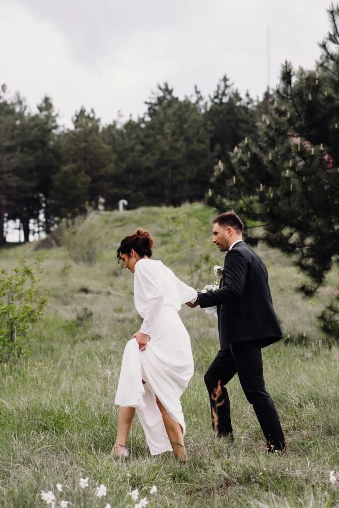 Groom leading the bride through the meadow grass