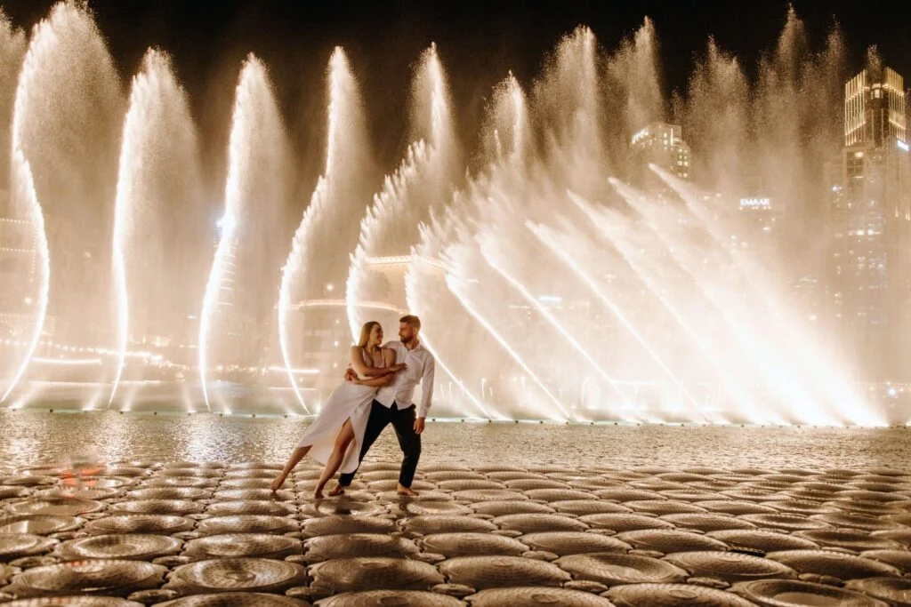 Couple dancing before the lit fountains at night