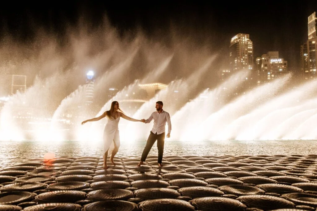 Couple walking hand in hand along the edge of the fountain pool