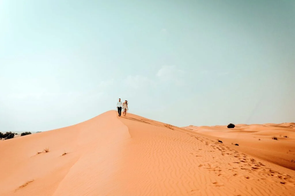 Couple on the ridge of a dune, footprints in the sand behind them