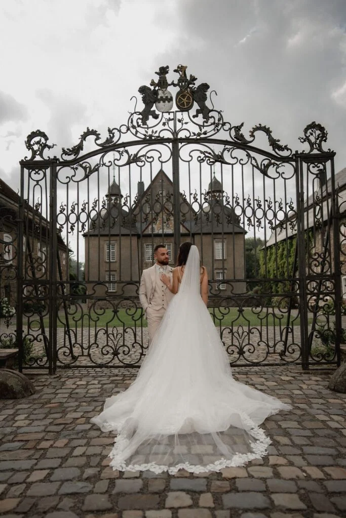 Bride and groom at the wrought iron gate of the castle in Germany