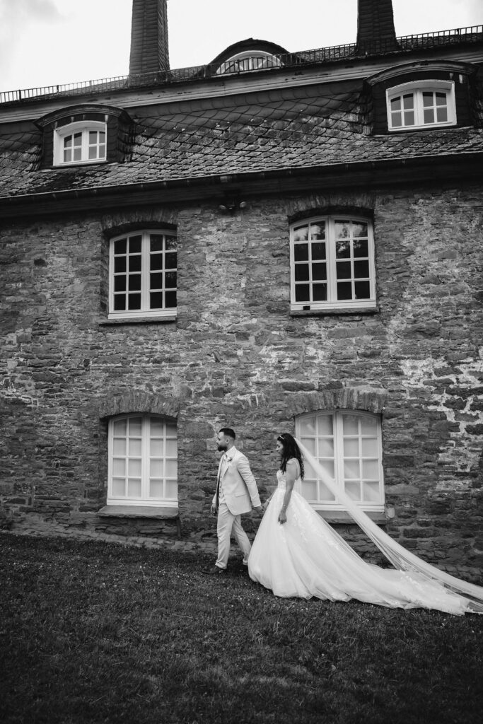 Black and white photograph of the couple beside a stone building at the castle