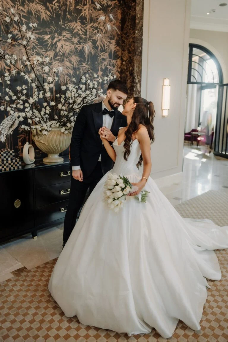 Bride and groom in a room with floral wallpaper and table lamps at Hotel Bristol