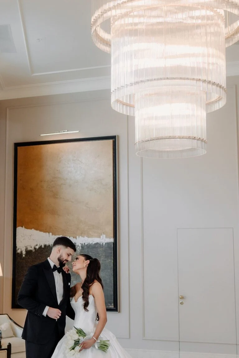 Bride and groom beneath a tiered chandelier at Hotel Bristol