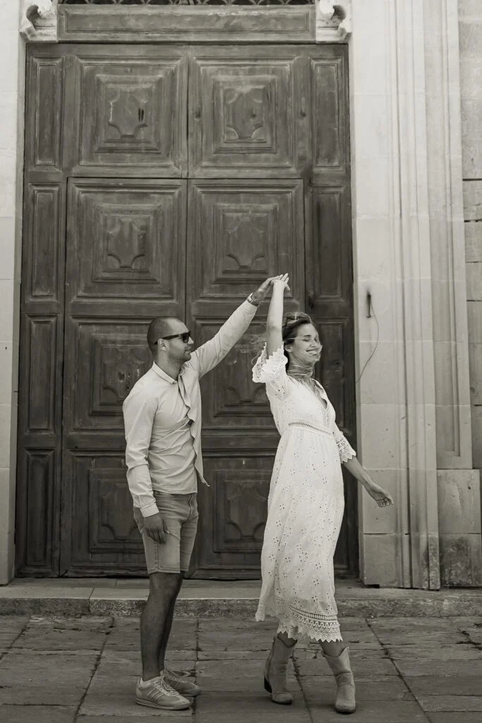 Black and white photograph of a couple dancing in front of a tall wooden door