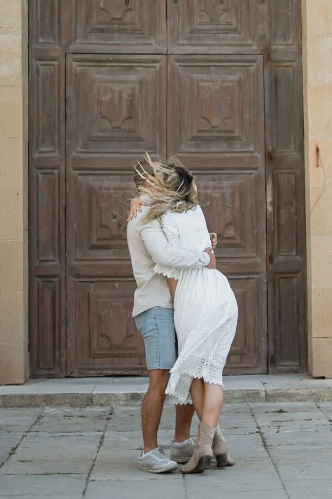 Couple embracing in front of a carved wooden door in Mdina