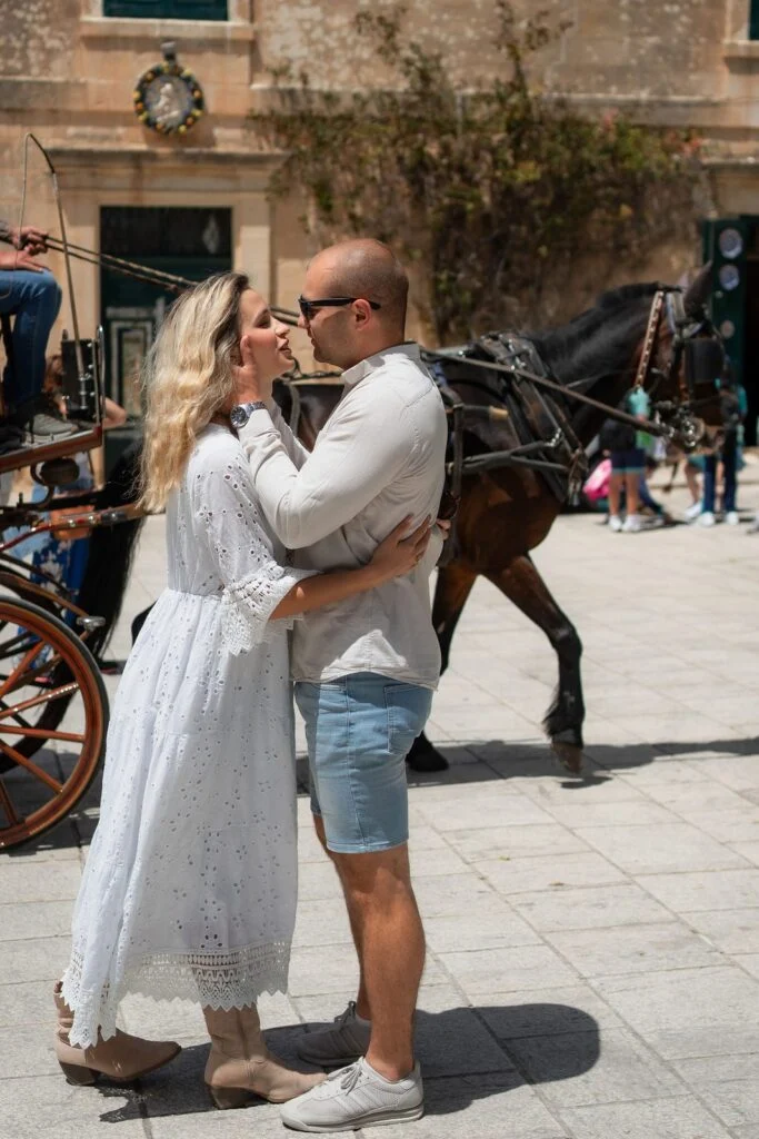 Couple kissing beside a horse drawn carriage in Mdina