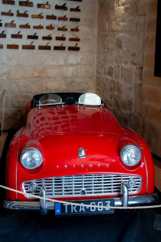 Red vintage sports car parked in a limestone courtyard