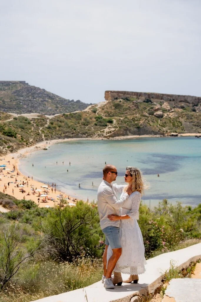 Couple standing above a beach and turquoise water