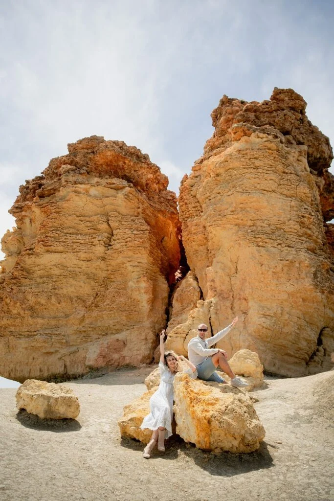 Woman seated between tall golden rock formations on the coast