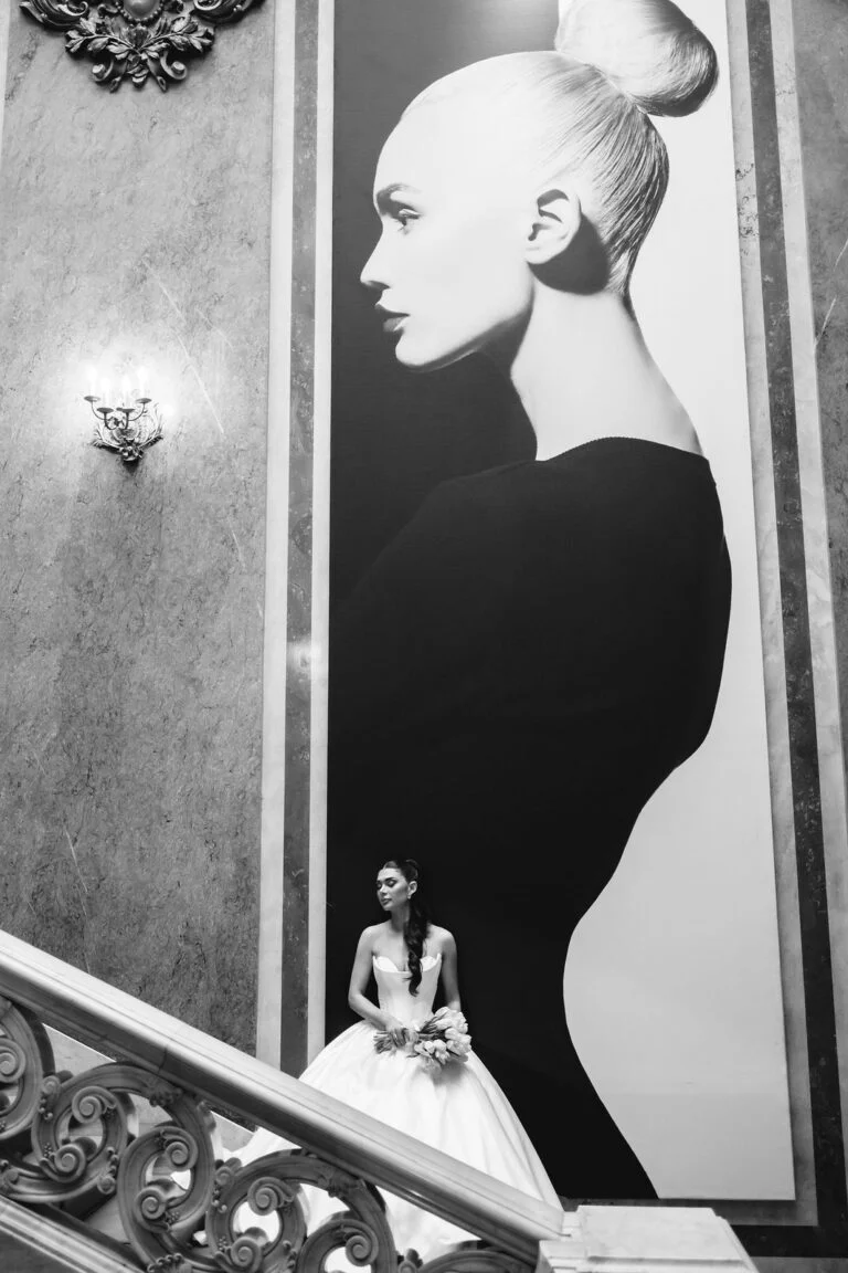 Bride standing beneath a large black and white portrait on the wall at Salon 1905