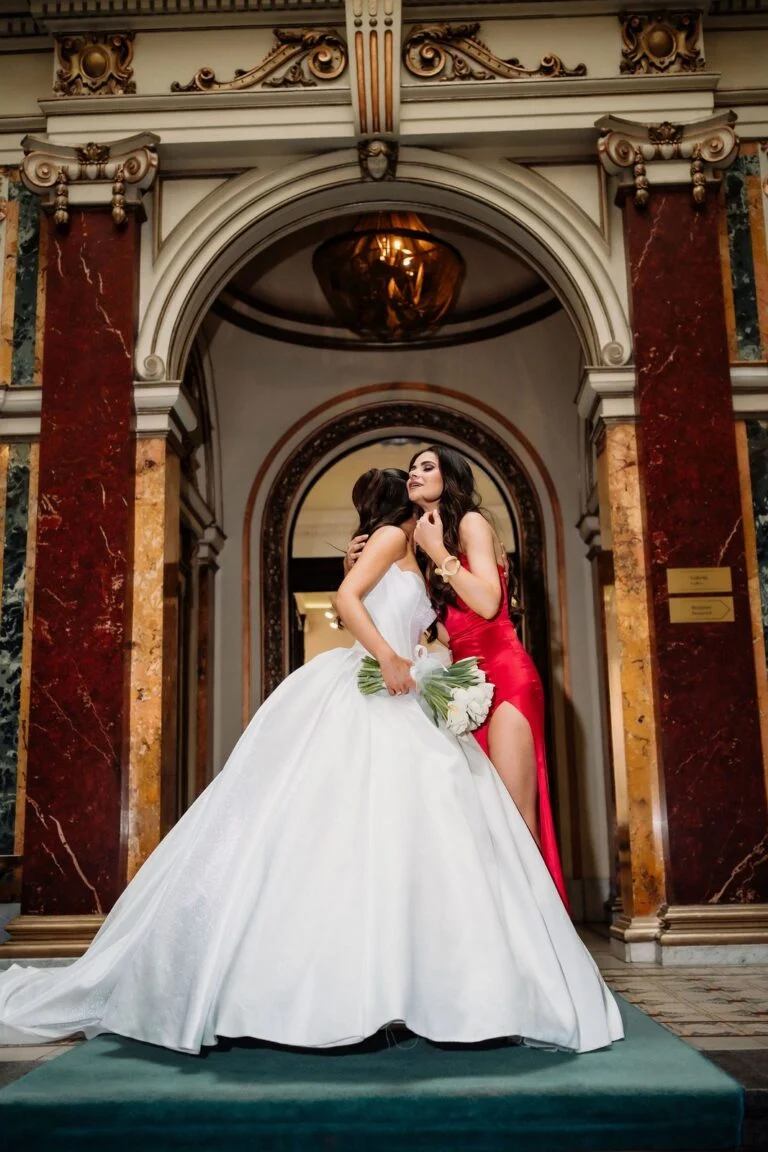 Bride and a woman in a red gown framed by the ornate doorway at Salon 1905