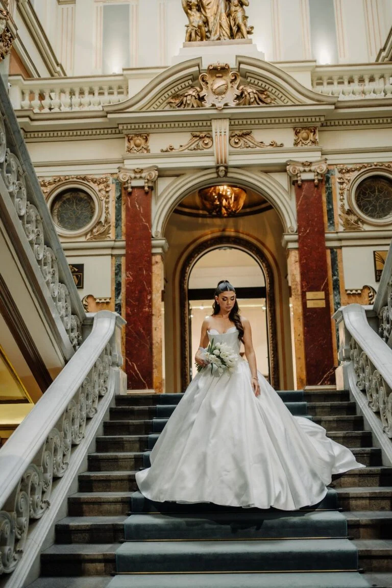 Bride standing at the foot of the ornate staircase at Salon 1905