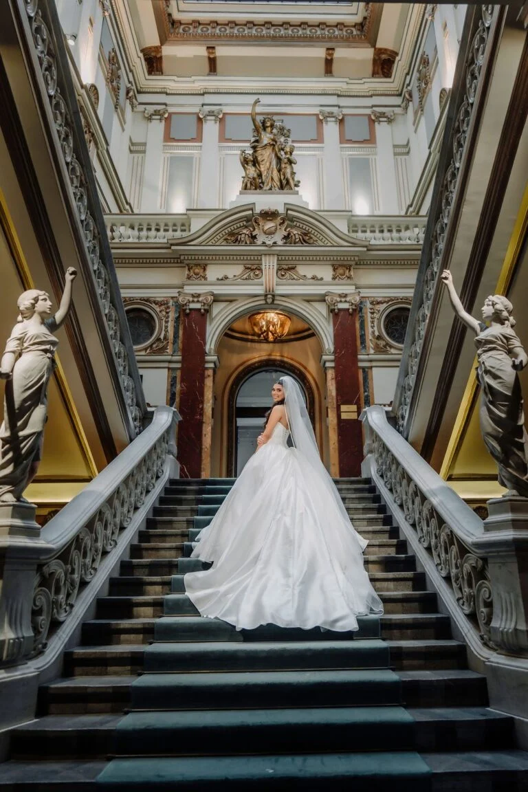 Bride on the staircase at Salon 1905 beside a marble statue