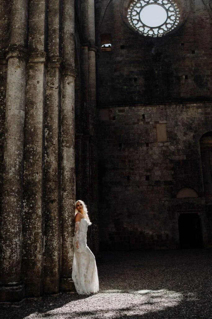 Bride standing in a shaft of sunlight inside the roofless abbey