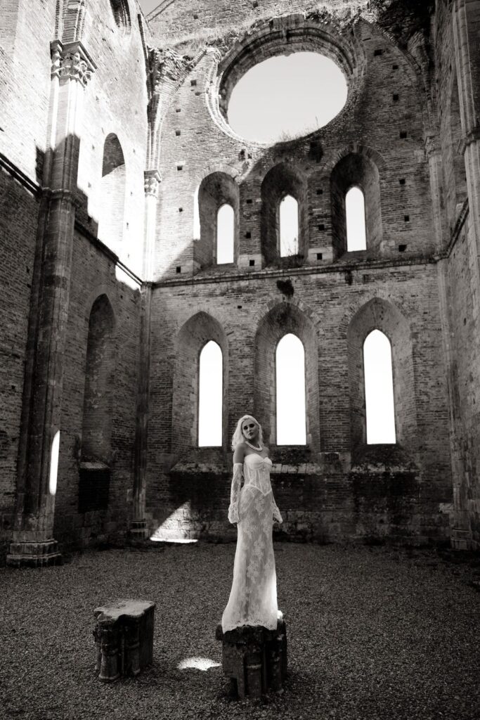 Black and white photograph of the bride in the abbey beside the arched windows
