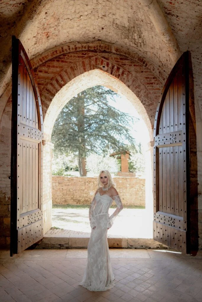 Bride framed in an arched doorway with a tree beyond