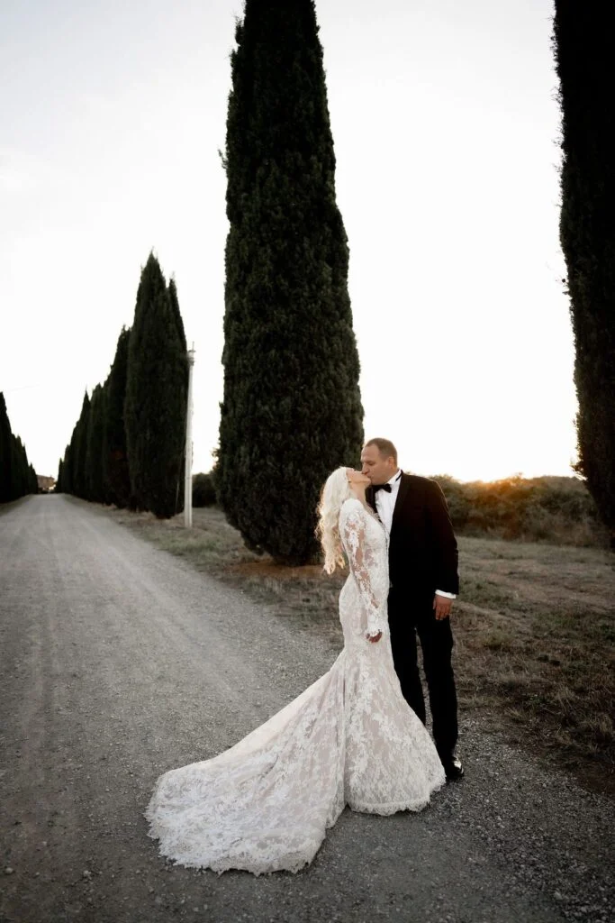 Bride and groom embracing on the cypress avenue at sunset