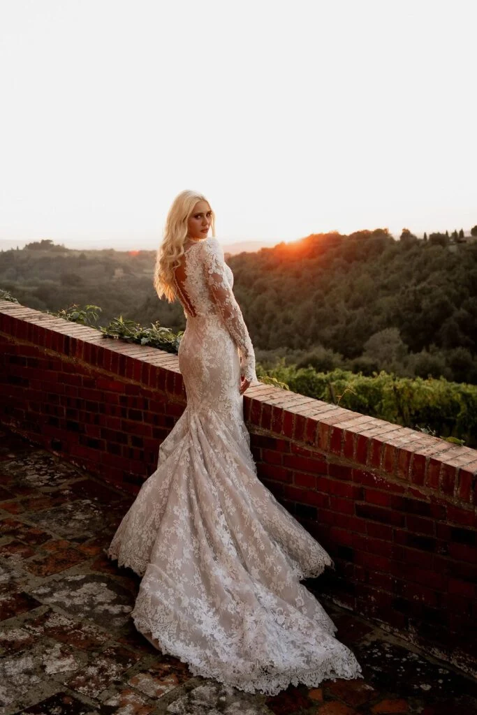 Bride on a brick terrace above the vineyards at sunset