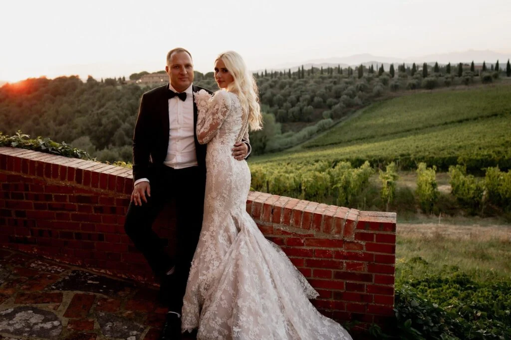 Bride and groom on the terrace above the vineyards, hills rolling away behind them