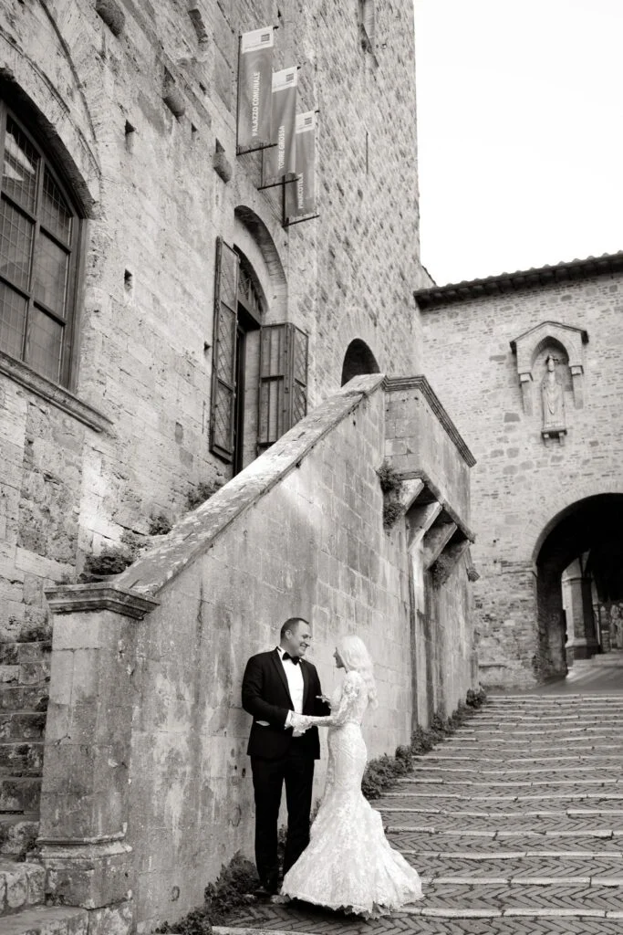 Black and white photograph of the couple on a stone staircase in a Tuscan town