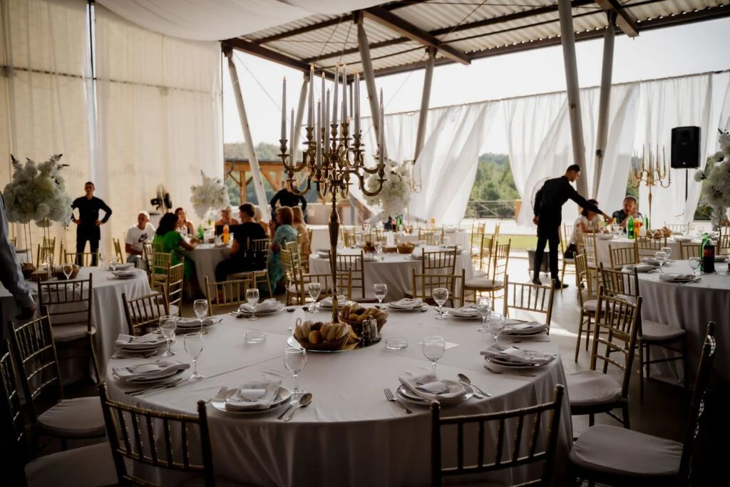 Round tables set under a marquee with chandeliers at an estate wedding