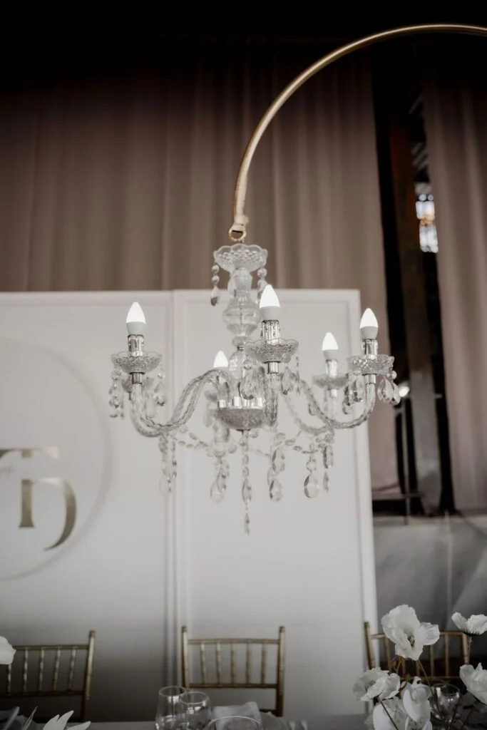 Crystal chandelier above a white ceremony backdrop